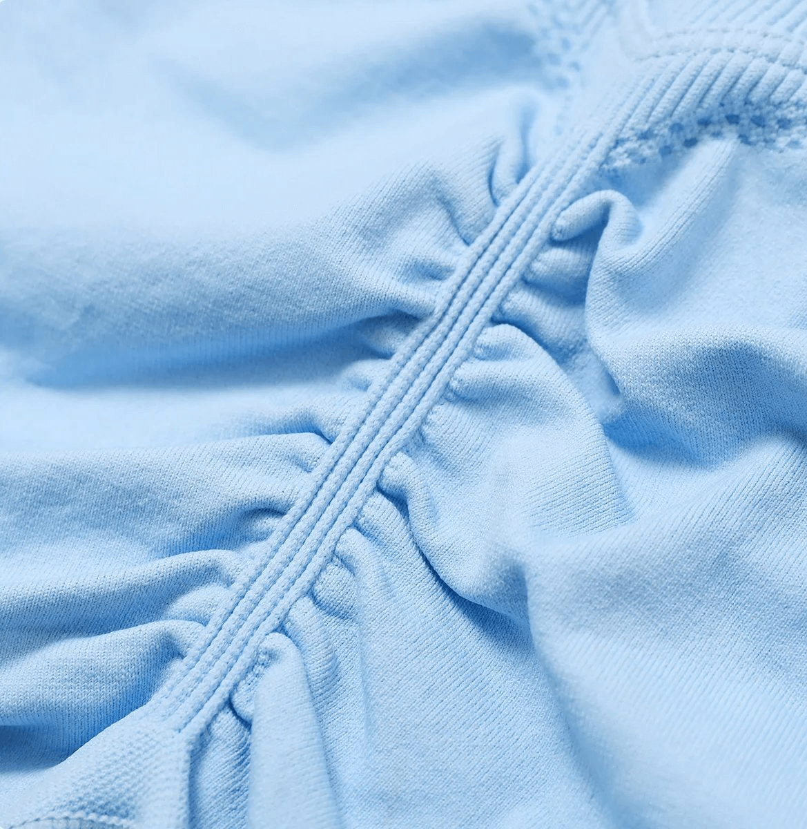Close-up of light blue fabric with ruched texture and decorative stitching, showcasing detailed craftsmanship and soft material.
