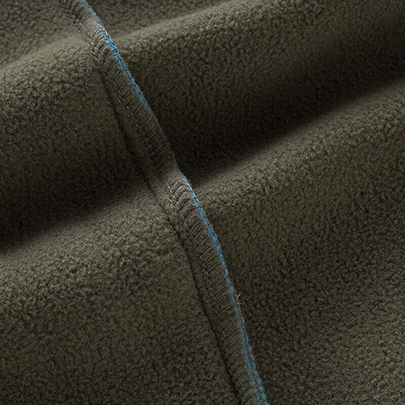 Close-up of olive green polyester fleece fabric with blue stitching, showcasing the texture and detail of the vest material.