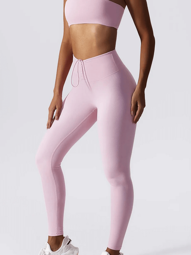 Woman wearing high waist pink leggings and push-up sports bra yoga set, showcasing fitness apparel.