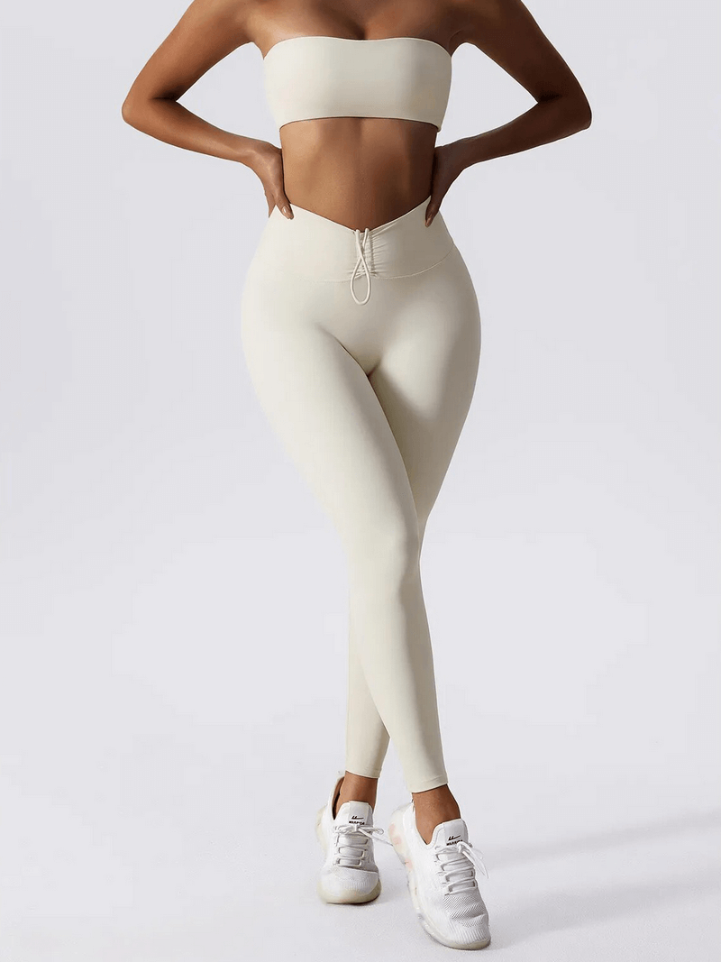 Woman wearing high waist leggings and push up sports bra yoga set, showcasing fitness attire in cream color.