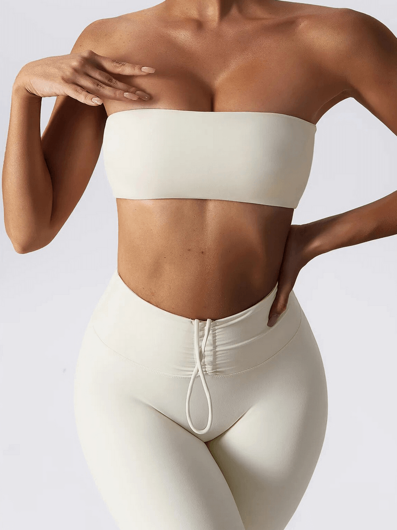 Woman modeling a stylish cream high waist leggings and strapless sports bra set, featuring a sleek design and comfortable fit.