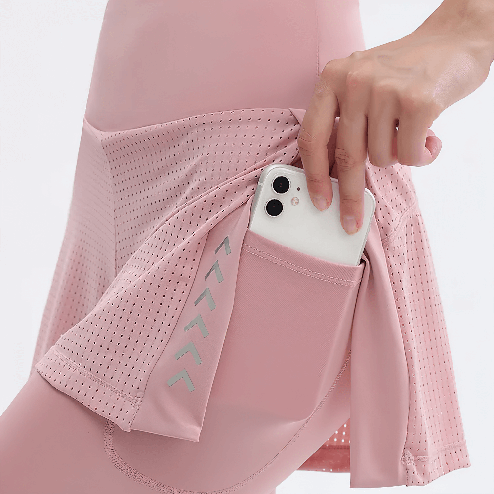 Close-up of pink high-waist yoga leggings with mesh shorts overlay and a pocket holding a smartphone, perfect for gym or running.