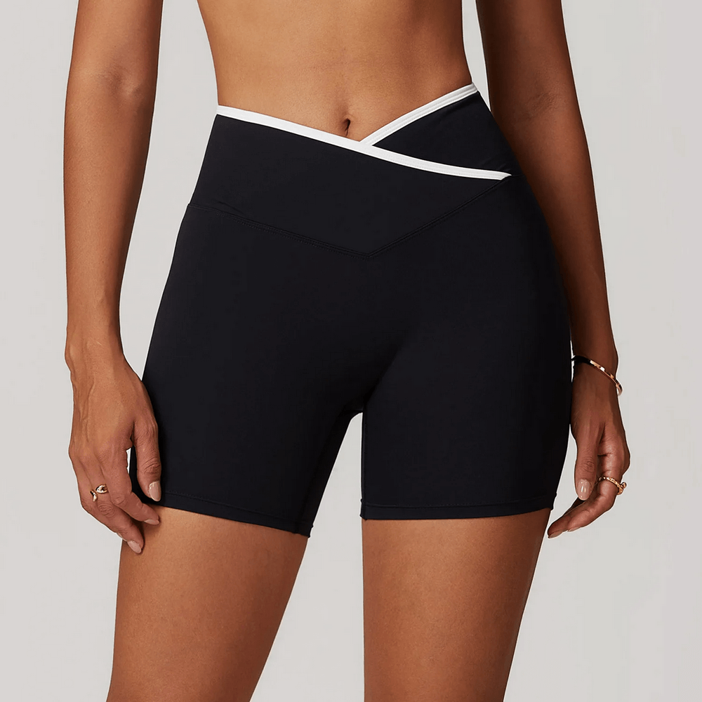 Woman wearing high waist yoga shorts with V-waist design, showcasing sleek fit for gym or lounging. Breathable stretch fabric for movement.