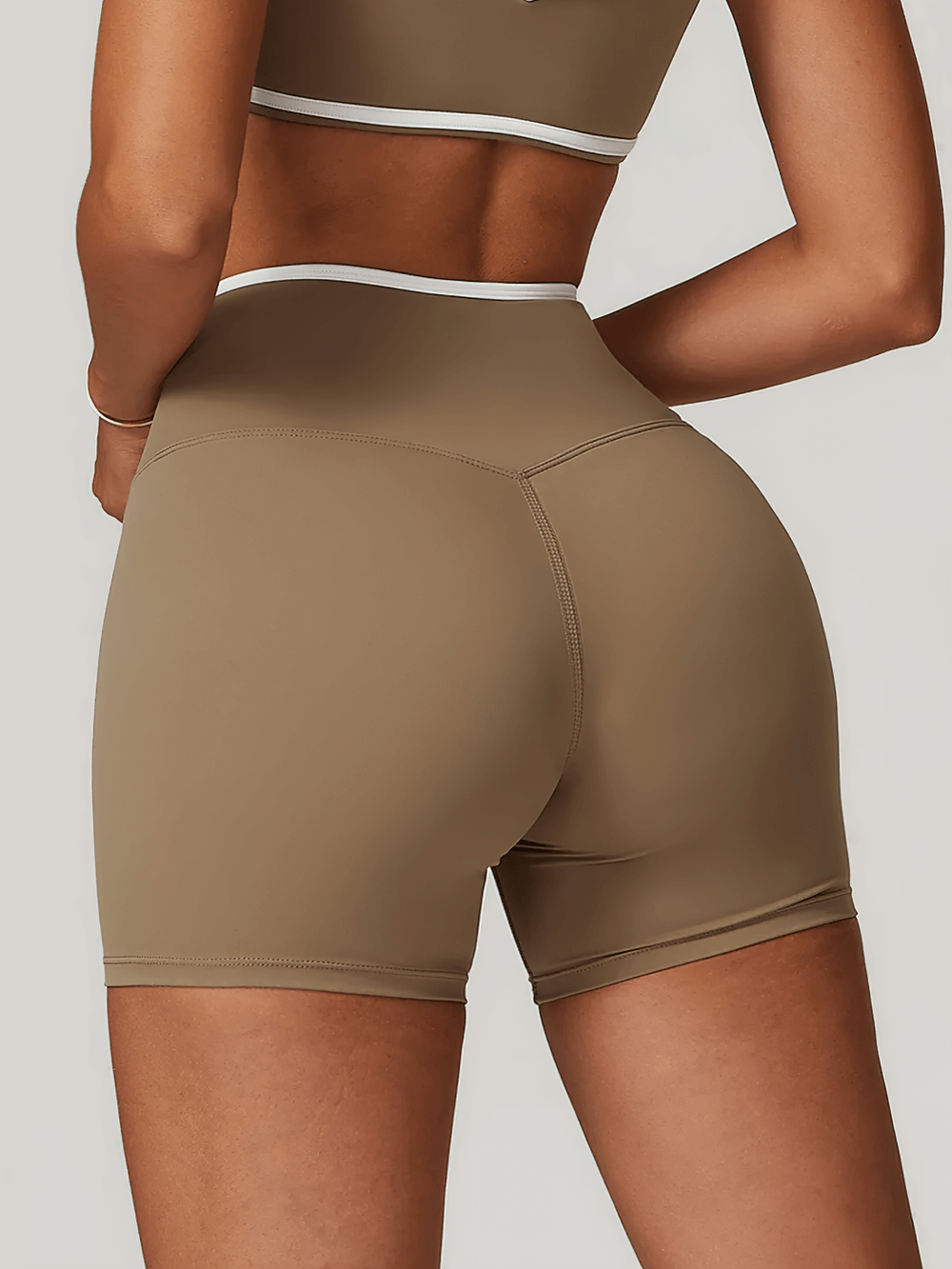 High waist yoga shorts with V-design, showing sleek fit for women, perfect for gym or running. Stretchy, breathable fabric in neutral tone.