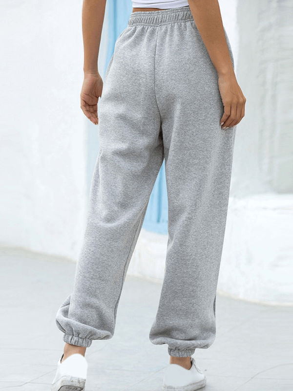 Model wearing high-waisted grey wide-leg sweatpants with pockets and elastic waist, perfect for casual comfort.