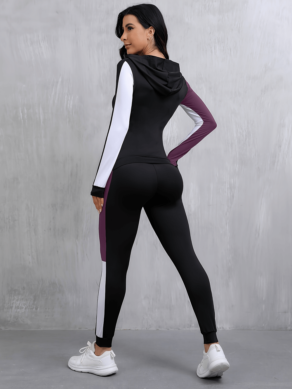 Woman wearing hooded color block sports tracksuit with pockets, featuring high-stretch design, perfect for yoga or casual outings.