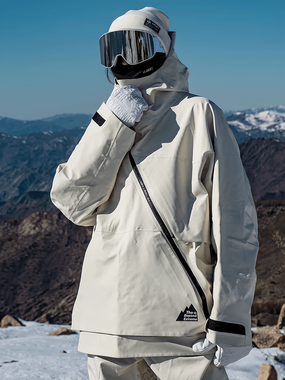 Alt Tag: Stylish waterproof white jacket with asymmetrical zipper, worn by model in snowy mountains; perfect for skiing or winter wear.