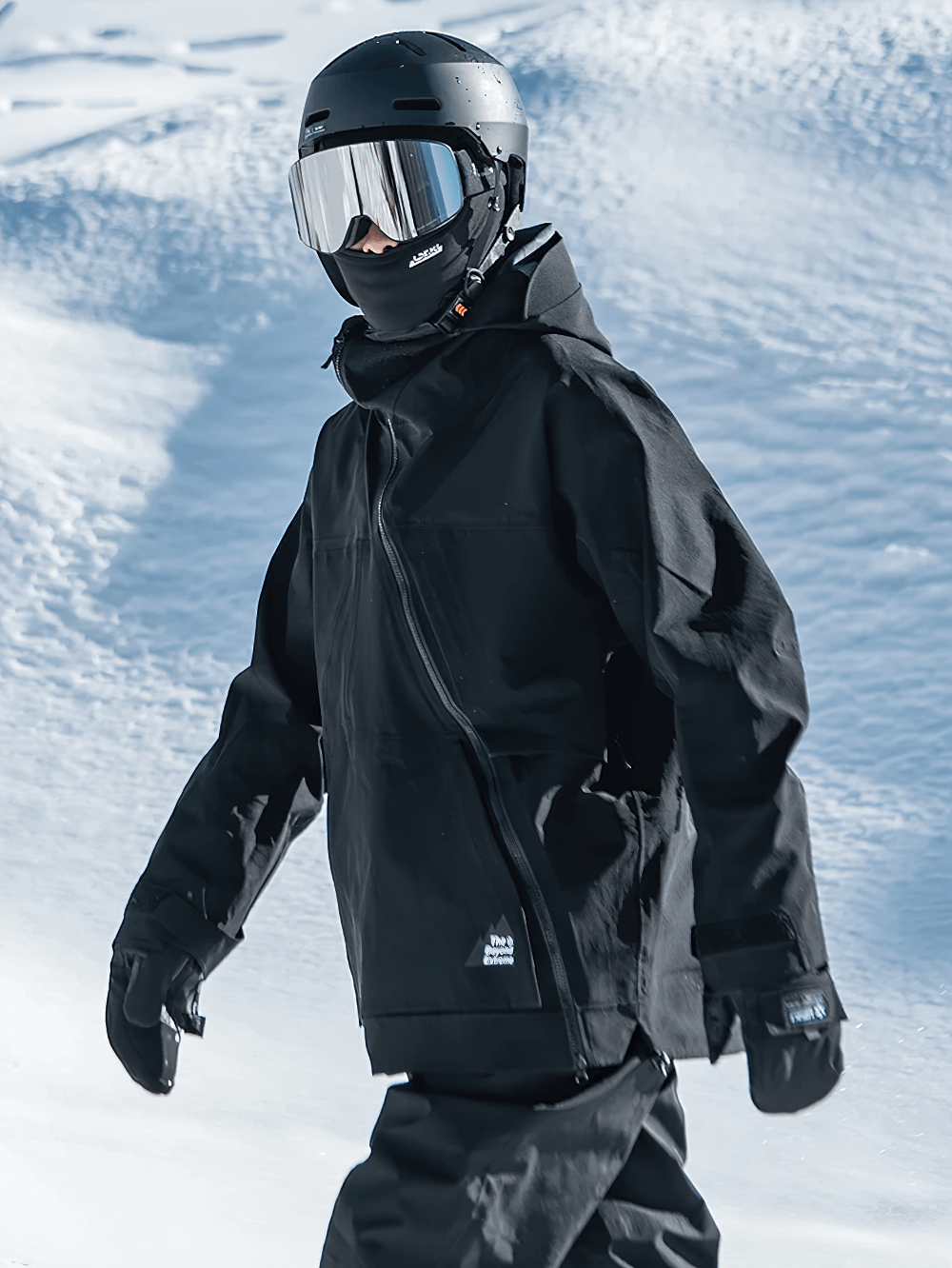 Person wearing black hooded waterproof jacket with asymmetric zipper in snowy landscape