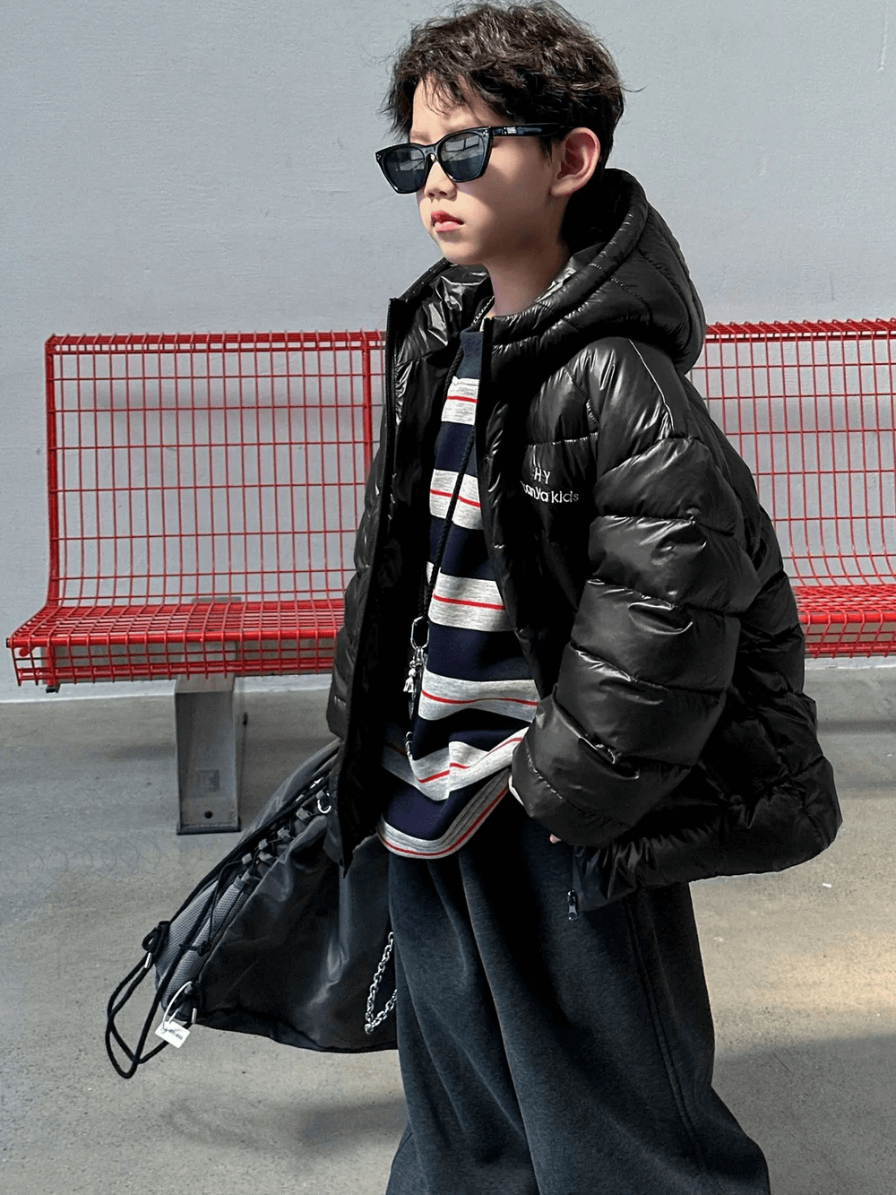 Boy wearing Hooded Puffer Jacket with Zipper and Insulation - SF3640, standing confidently with red bench background.