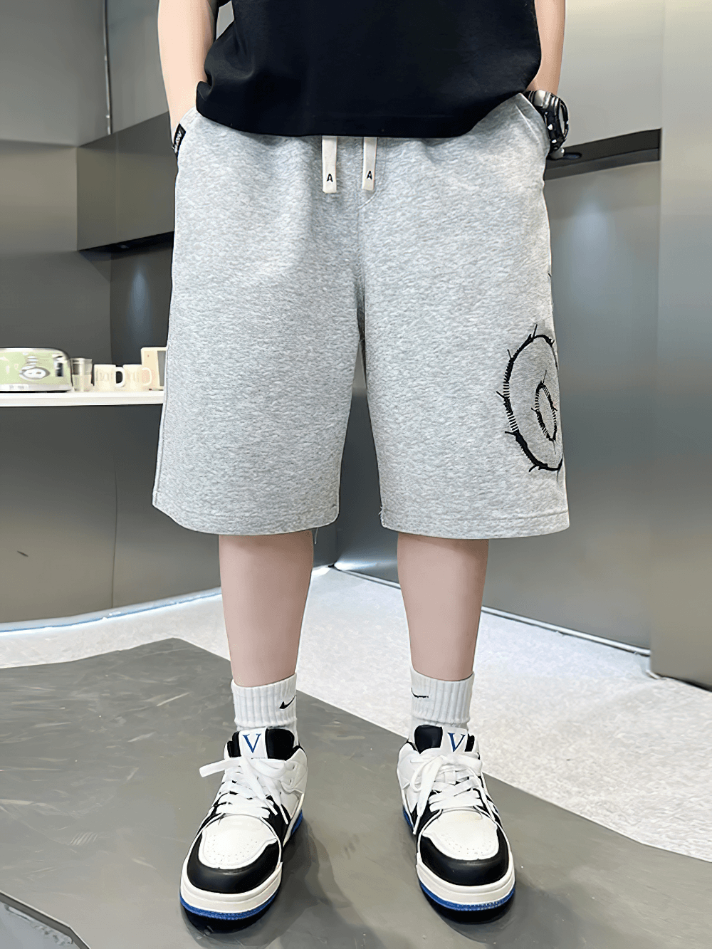 Kid wearing grey Kids Baggy Cotton Shorts with Graphic Print - SF3891, featuring elastic waistband and bold letter print.