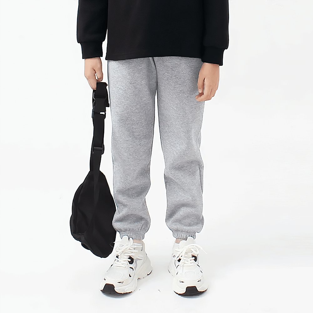 Child wearing gray Kids Casual Sports Jogger Pants with Pockets - SF3612, holding a black bag, showcasing comfort and style.