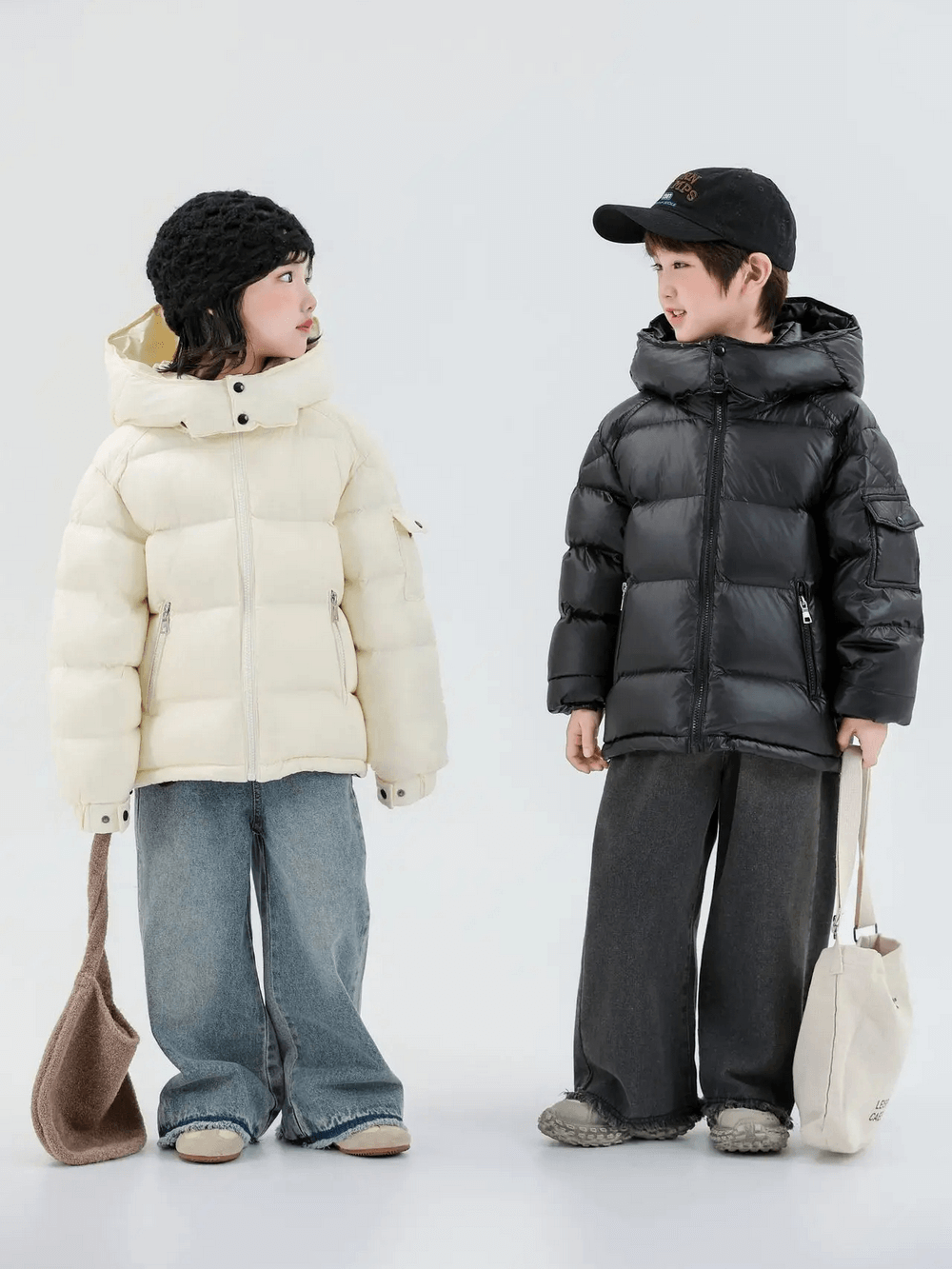 Two kids wearing puffer coats, one in a white jacket and jeans, the other in black, showcasing Kids Duck Down Jacket with Hood and Zipper - SF3515
