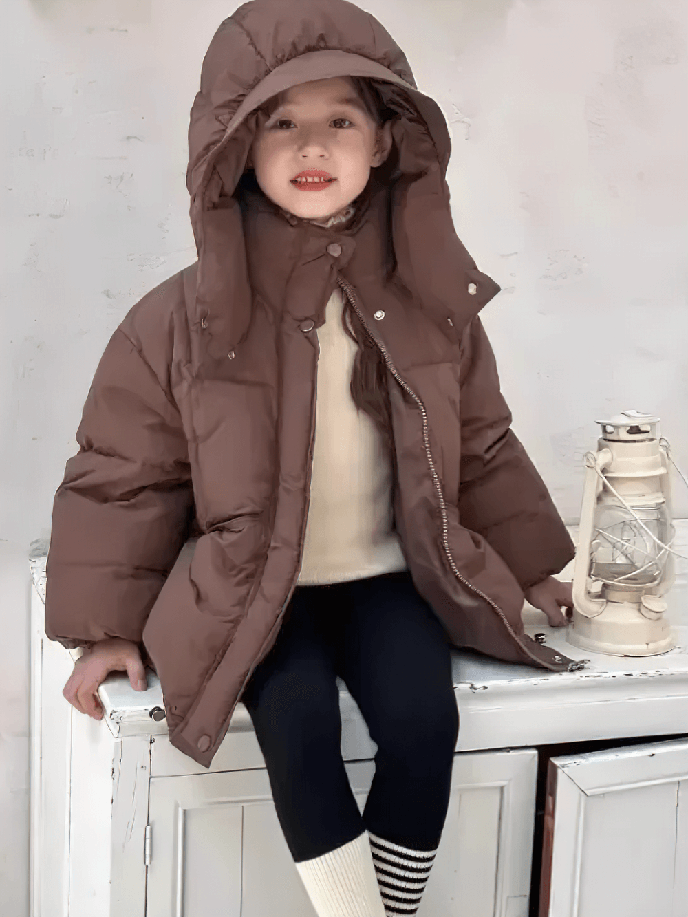 Child wearing Kids Hooded Down Jacket With Warm Thicken Padding - SF3809, sitting with a lantern on a white cabinet.