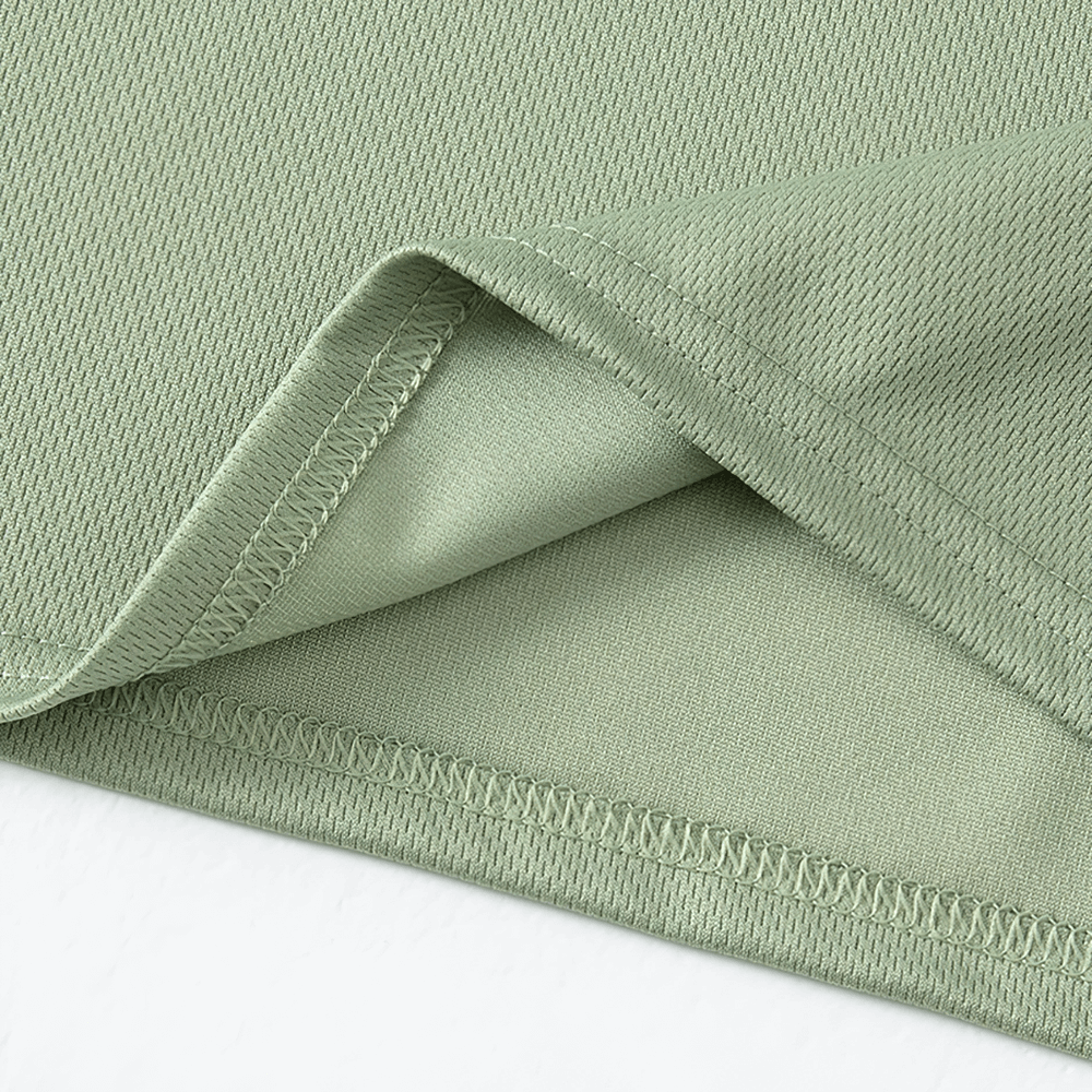 Close-up of green quick-drying kids sport t-shirt fabric showcasing stitching detail for durability and softness.