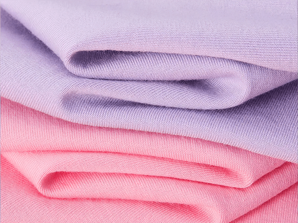 Soft folded cotton fabric in pastel purple and pink shades, ideal for crafting and sewing projects.