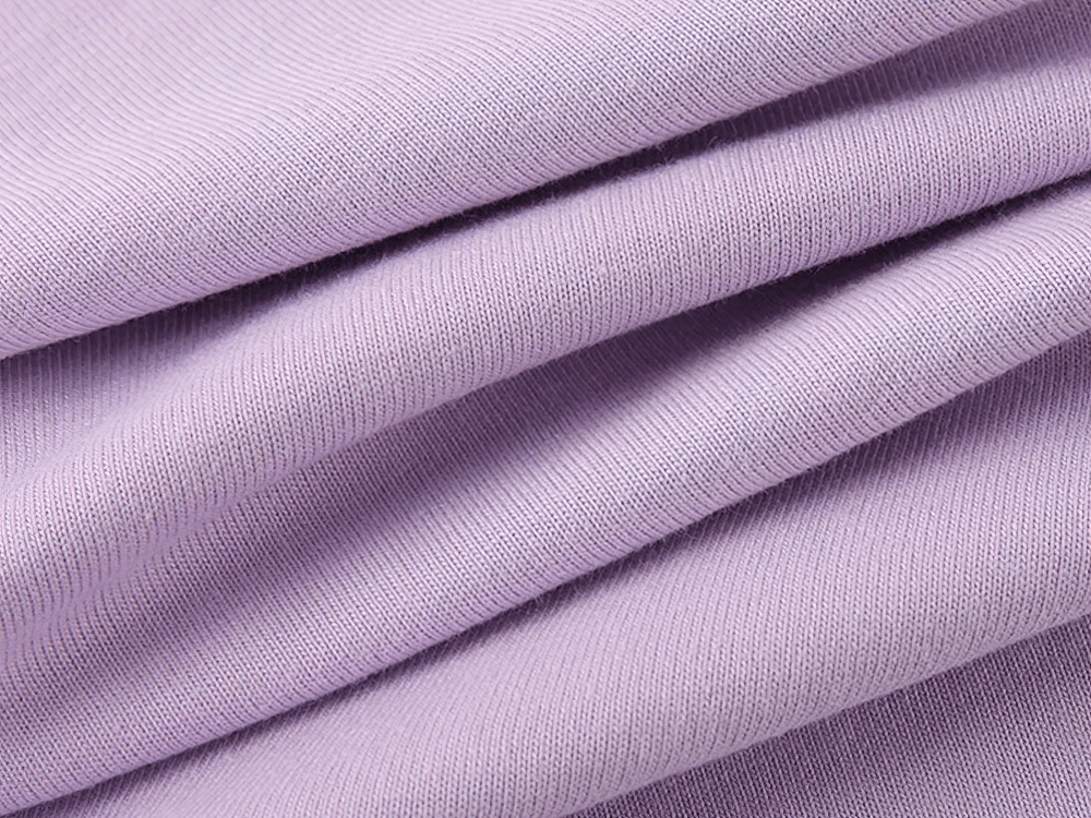 Close-up fabric texture of a lilac short-sleeved cotton T-shirt for kids, showcasing smooth and soft quality material.