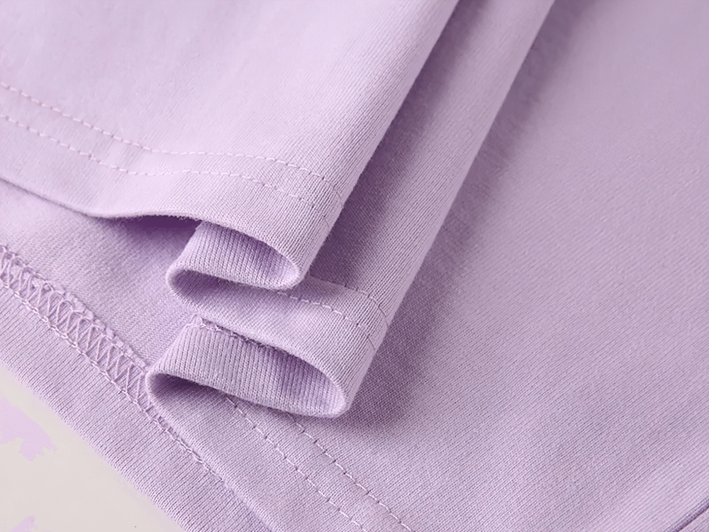 Close-up of kids solid color cotton T-shirt sleeve in soft lavender, emphasizing quality stitching and fabric detail.