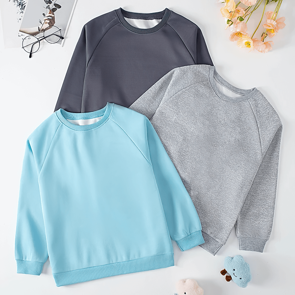 Three kids' solid color sweatshirts, in blue, dark gray, and light gray, displayed with flowers and toys for everyday wear - SF3093.