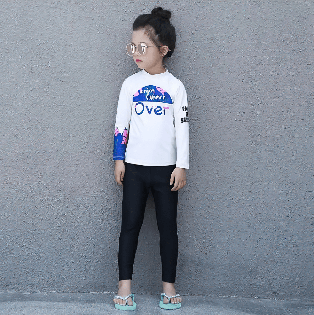 Young girl posing in Kid's Sport Long Pants with Quick Dry Fabric - SF3586, wearing stylish swim top and sunglasses against a gray wall.
