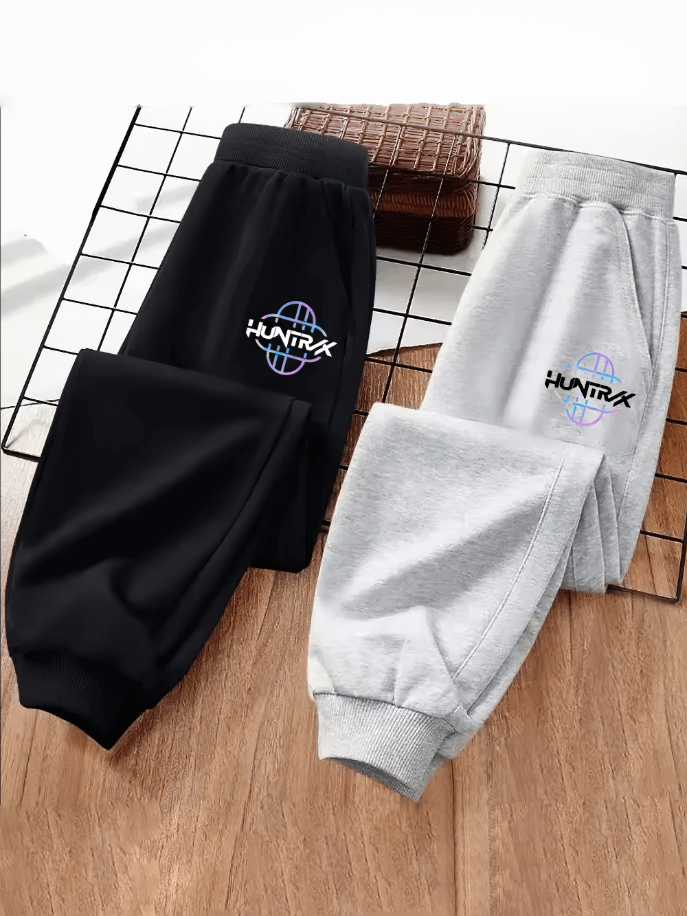 Kids Sporty Jogger Pants with Elastic Cuffs - SF3882 in black and grey featuring bold printed logos on a wooden grid display.