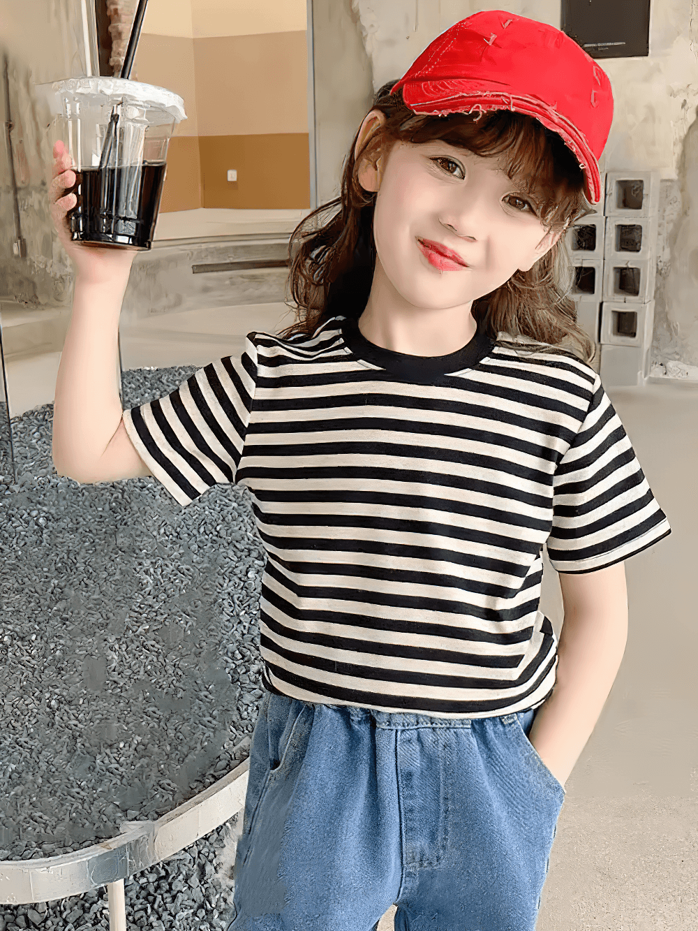 Child wearing Kids Striped Short-Sleeved T-Shirt for Simple Look - SF3711 with red cap, holding a drink, smiling indoors.