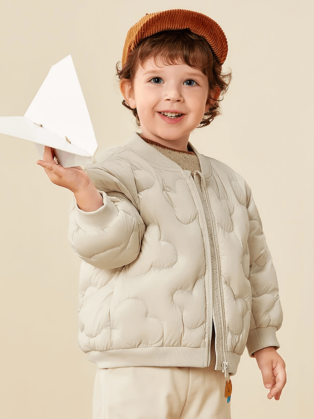 Kid wearing Kids Windproof Down Jacket with Cloud Design - SF3703, holding a paper plane and smiling.