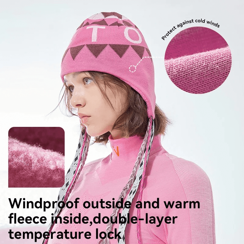 Woman wearing pink knitted ski hat with ear flaps and stylish print, highlighting windproof, fleece features for winter coziness.