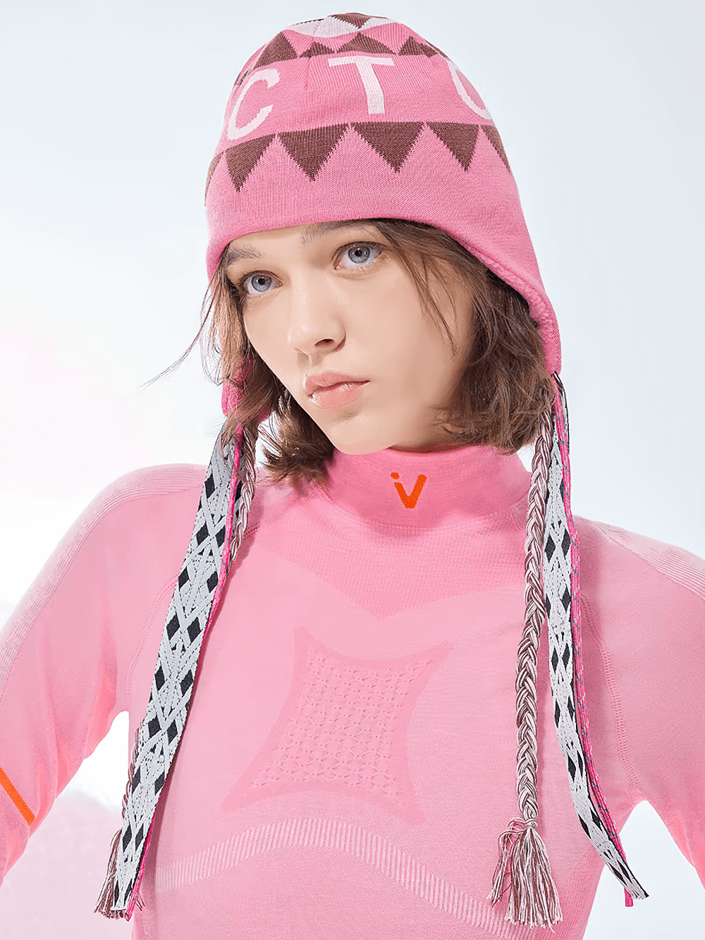 Woman wearing pink knitted ski hat with ear flaps and boho design, ideal for winter skiing and outdoor adventure fashion.