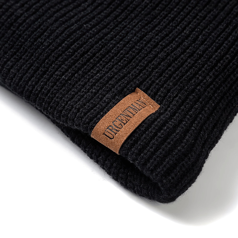 Close-up of a black knitted winter beanie hat with a brown label, perfect for cozy seasonal wear.