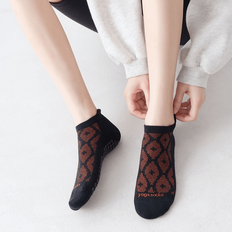 Woman wearing black and red geometric anti-slip Pilates socks, showcasing breathable cotton and comfort for casual sports.