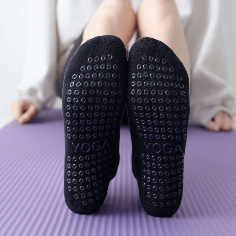 Black ladies' anti-slip cotton Pilates socks on yoga mat, showcasing grip dots and breathable design for workout comfort.