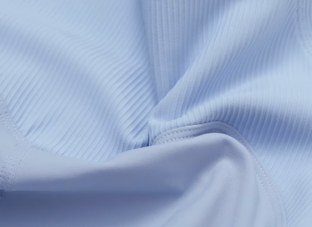 Close-up of light blue ribbed women's sports tank top fabric showcasing breathable, lightweight material.