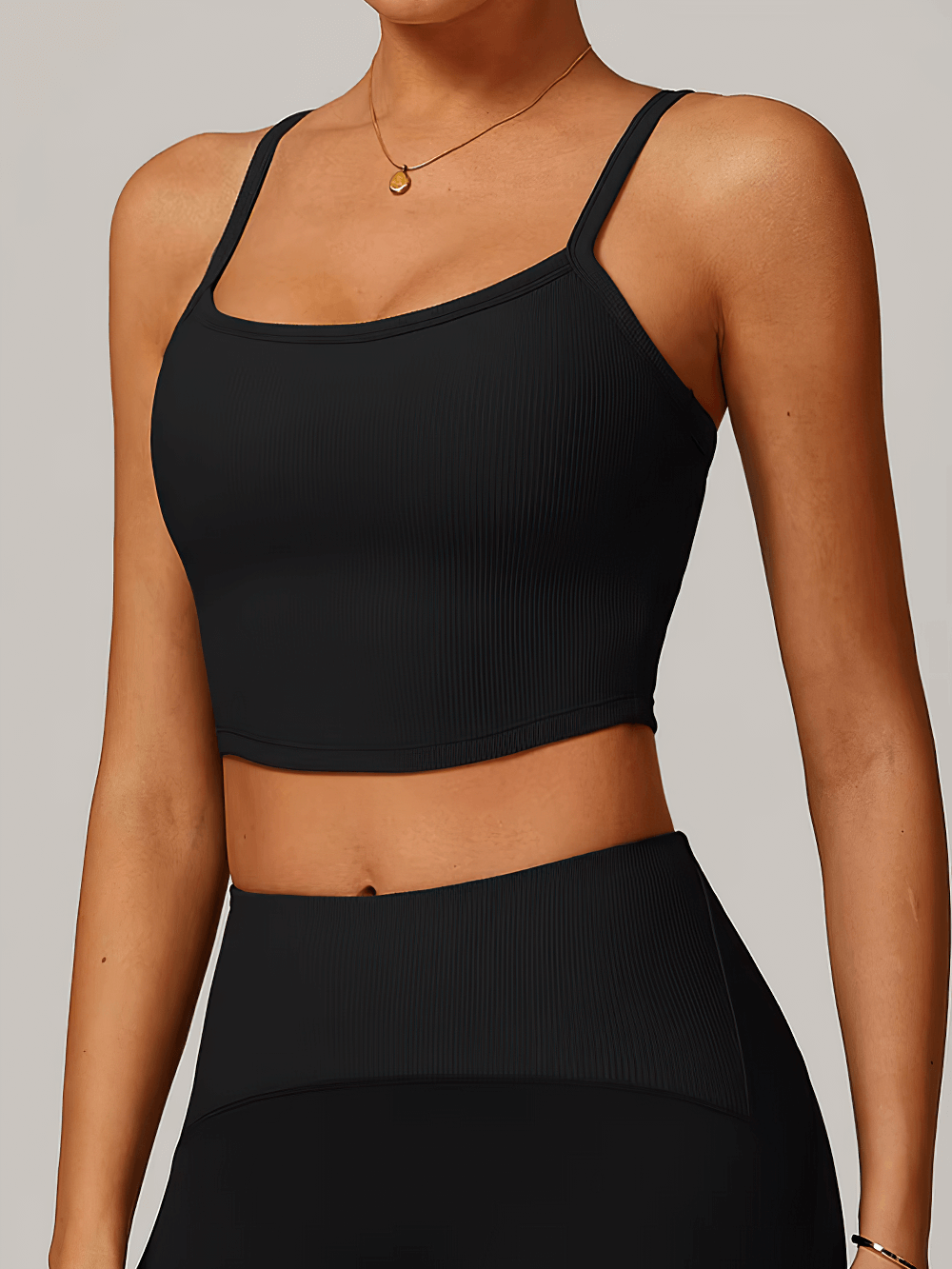 Woman wearing black ribbed racerback sports tank top, perfect for yoga, running, and workouts. Lightweight and breathable design.