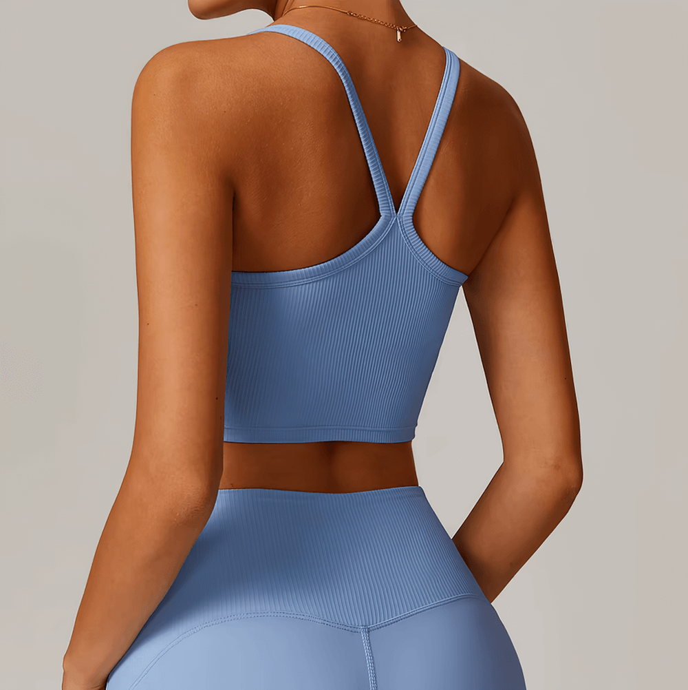 Woman wearing a blue ribbed racerback sports tank top, showing the stylish open back design. Perfect for yoga and workouts. SF2444