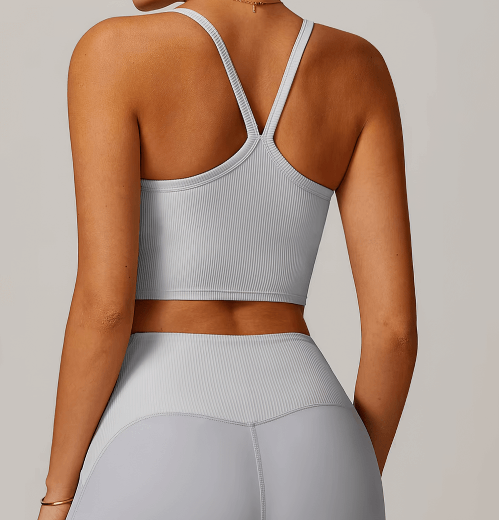 Woman wearing a stylish ribbed racerback sports tank top in gray, ideal for workouts like yoga and running. Lightweight and breathable design.