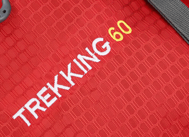 Close-up of red travel backpack featuring TREKKING 60 label, ideal for outdoor adventures.