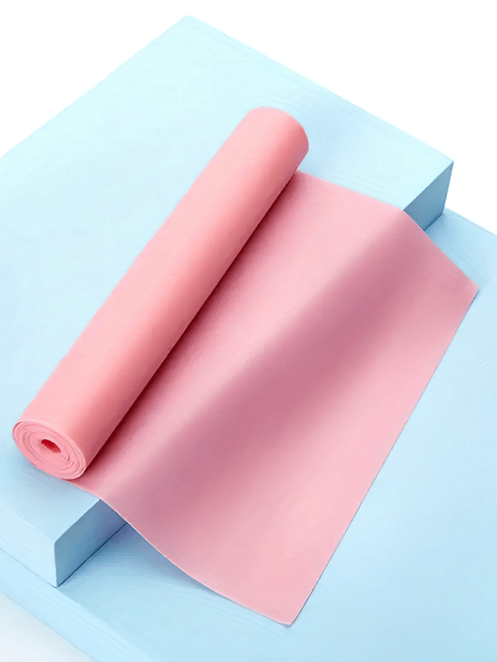 Pink latex resistance band for yoga and Pilates, rolled on a vibrant blue surface.