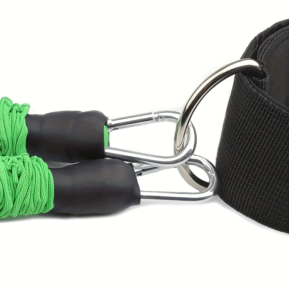 Close-up of green leg resistance bands with metal clips attached to a black ankle strap for lower body workouts.