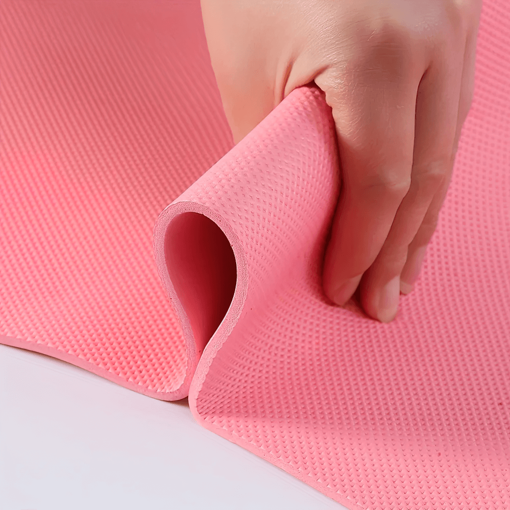 Close-up of a pink EVA yoga mat being rolled, showcasing its lightweight, non-slip surface, perfect for home gym fitness sessions.