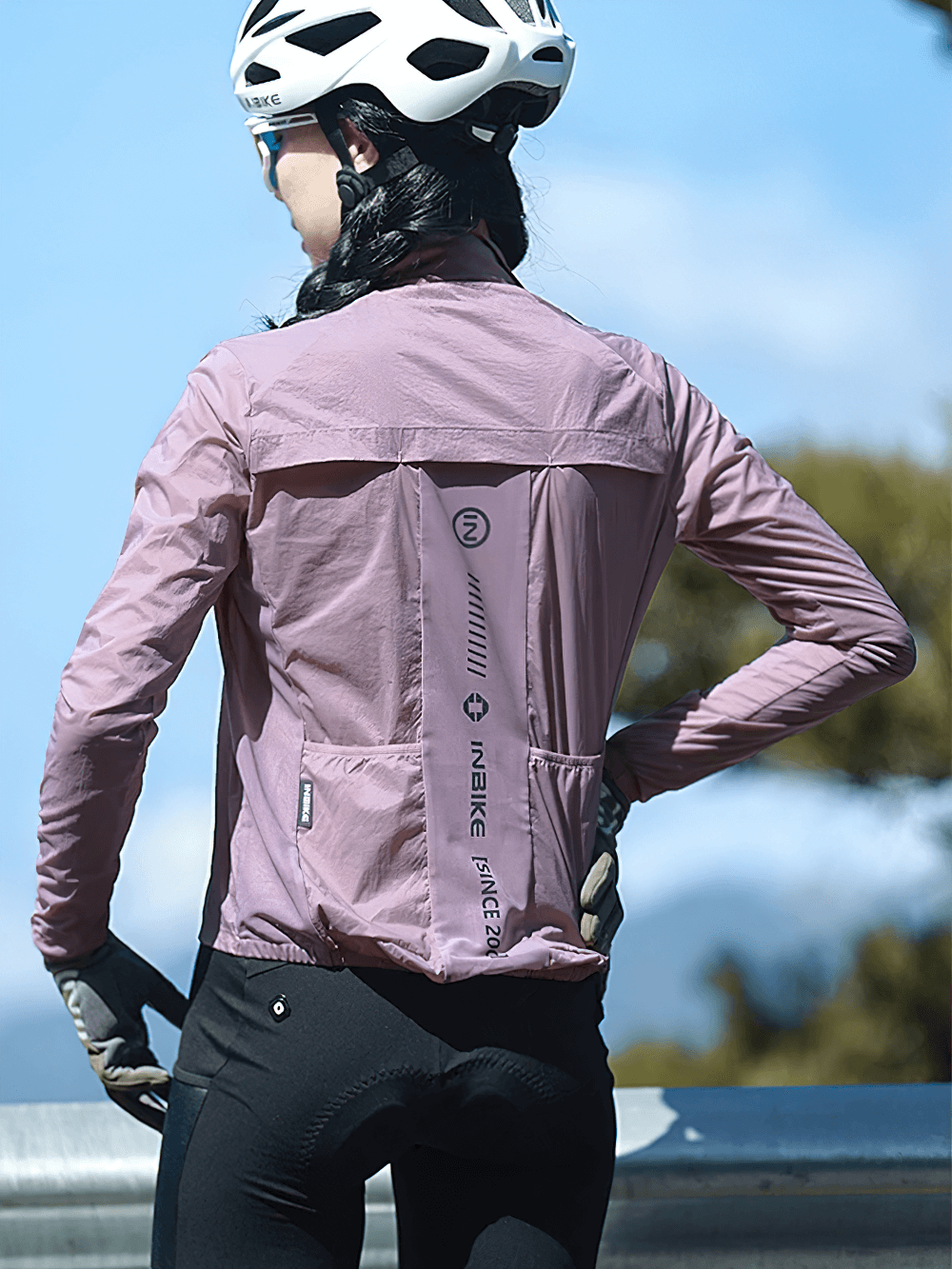 Woman wearing lightweight cycling jacket with reflective details and elastic cuffs in outdoor setting