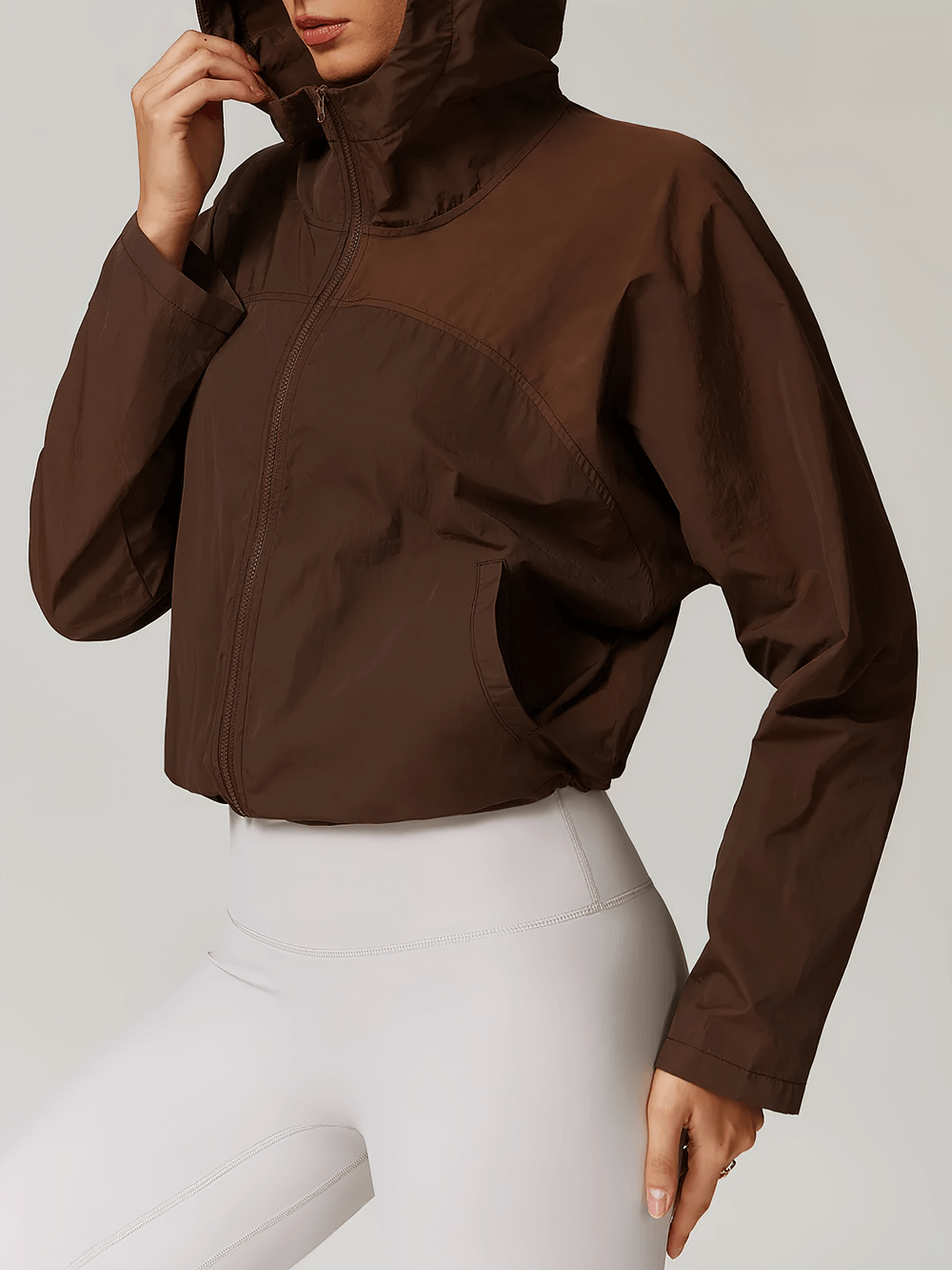 Lightweight brown hooded jacket for active women, with adjustable features and breathable fabric, ideal for outdoor activities.