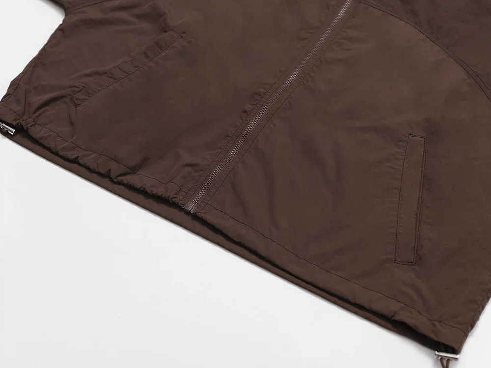 Close-up of brown lightweight hooded jacket with zippered pocket, designed for active women. Perfect for outdoor activities and casual wear.