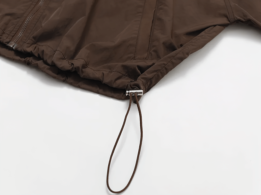 Close-up of brown lightweight windbreaker with adjustable drawcord hem, ideal for outdoor activities and casual wear.