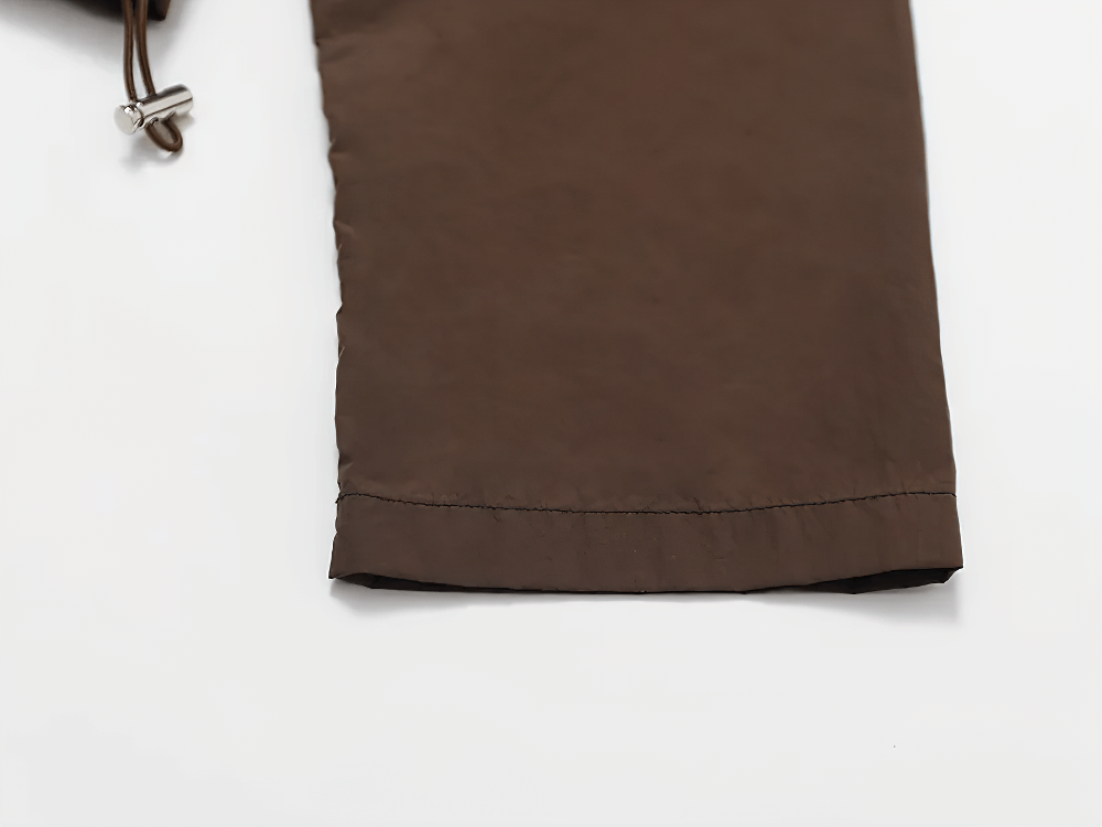 Close-up of the brown lightweight hooded jacket's sleeve, showing breathable fabric and drawcord hem detail, perfect for active women.