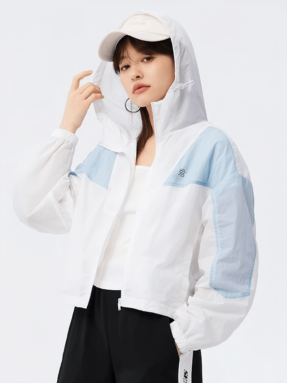 Woman wearing a lightweight hooded windbreaker with blue and white colorblock design, perfect for outdoor activities.