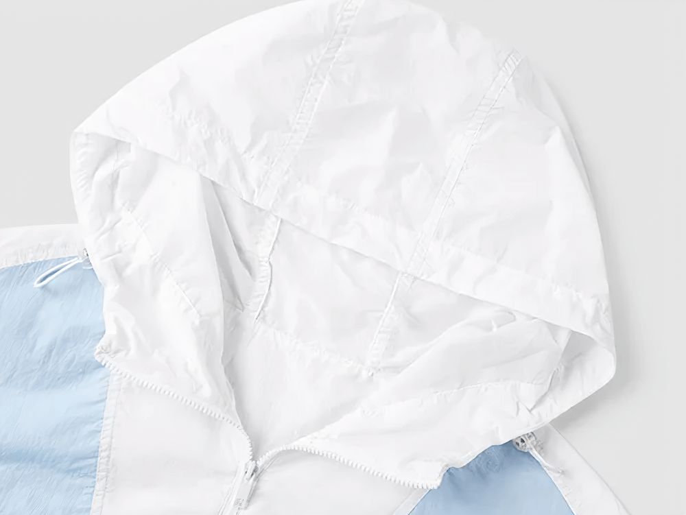 Close-up of lightweight women's windbreaker featuring a white hood and colorblock design, ideal for outdoor sports and casual outings.