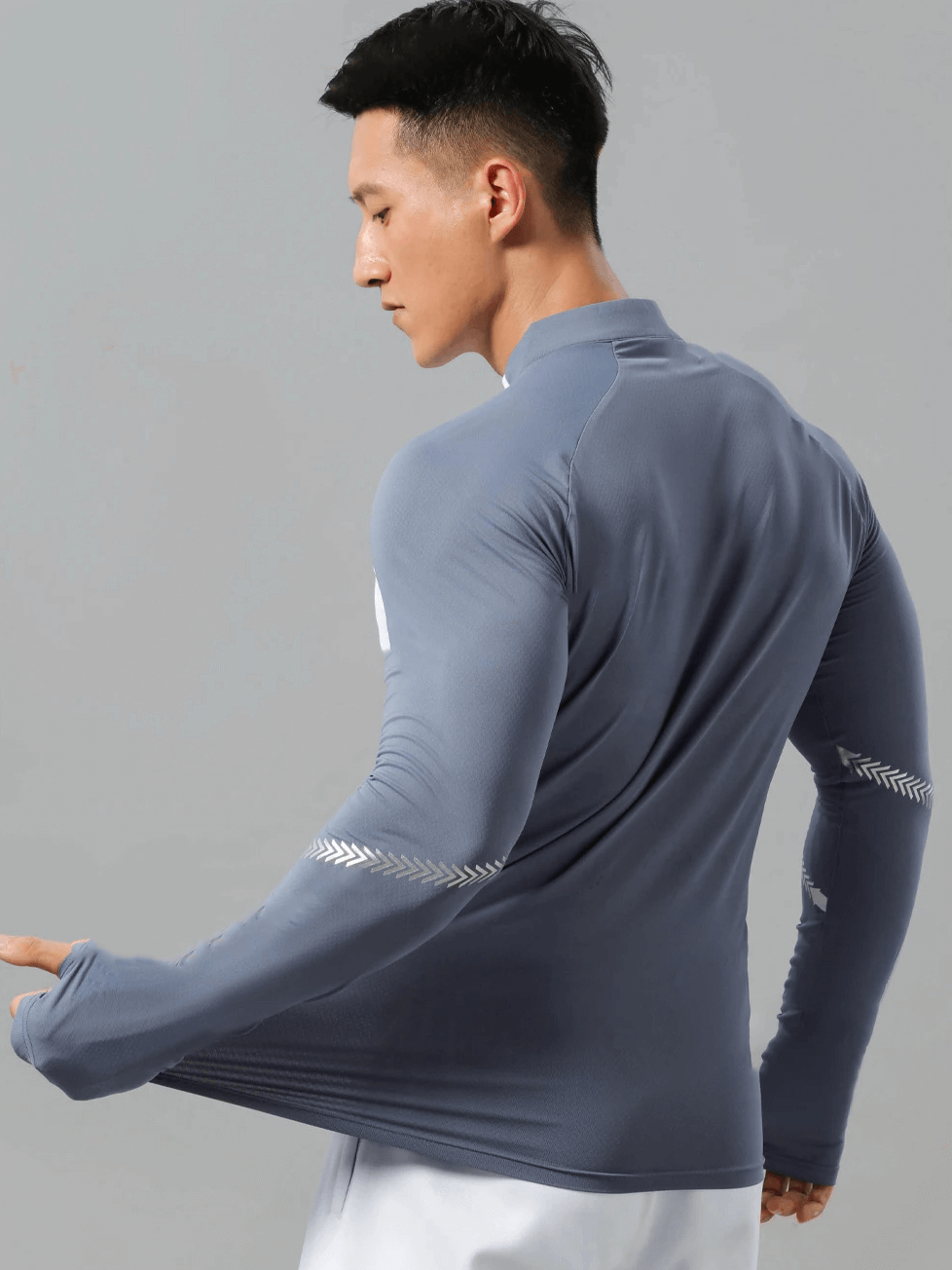 Back view of man wearing a lightweight long-sleeved zip shirt in gray with patterned sleeves, designed for athletic performance and style.
