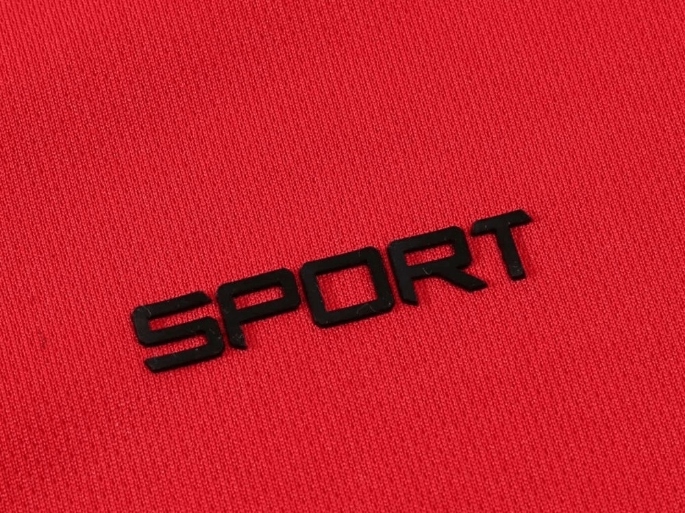 Close-up of red polyester fabric with the word 'SPORT' in bold black letters, representing athletic clothing material.
