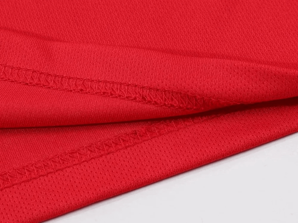 Close-up of red breathable fabric from men's athletic T-shirt, showcasing detailed stitching and lightweight material.