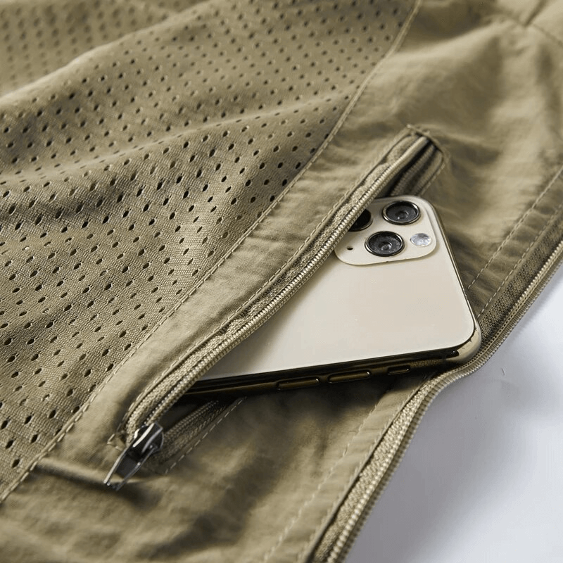 Close-up of tan lightweight men's vest pocket with a smartphone partially zipped inside, showcasing practical design.
